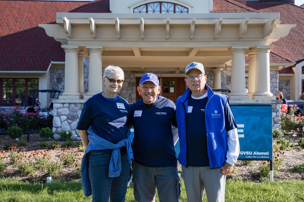 3 class of 1967 Alumni stand in front of Alumni House and Visitor's Center